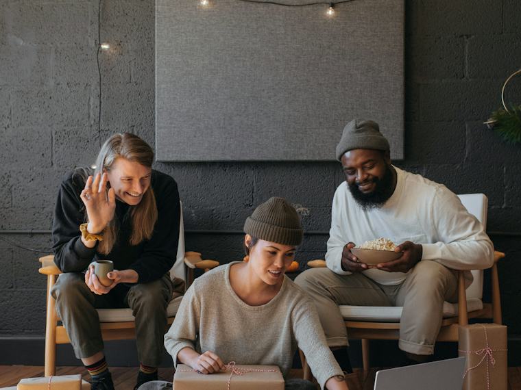 Three people talking with a colleague over a video call on a laptop